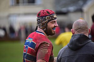 A man in a scrum cap and red and blue striped rugby kit.